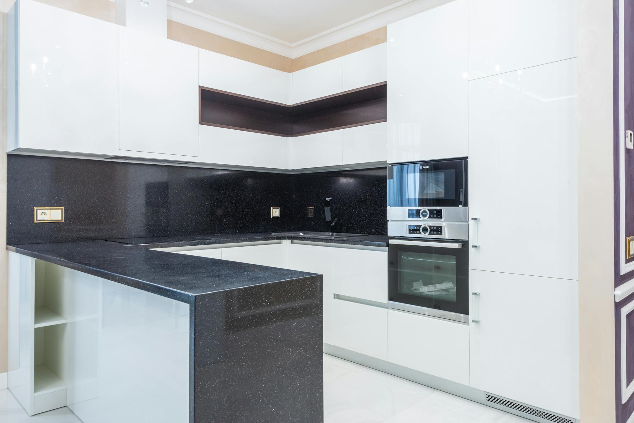 Explore a sleek and modern kitchen with white cabinetry and black countertops.